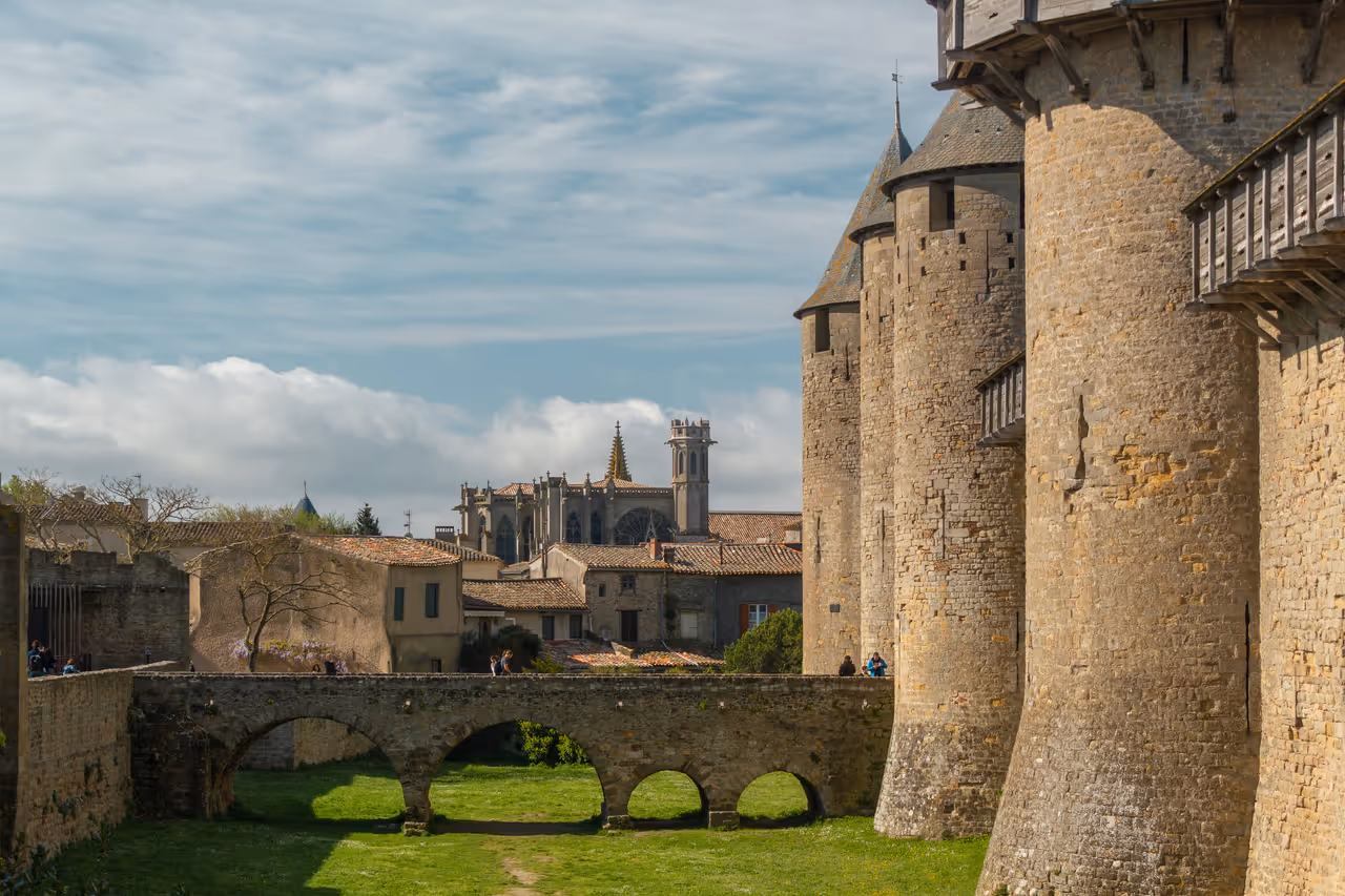 Stone bridge leading to the massive stone towers of the Château Comtal inside the medieval fortified Cité de Carcassonne