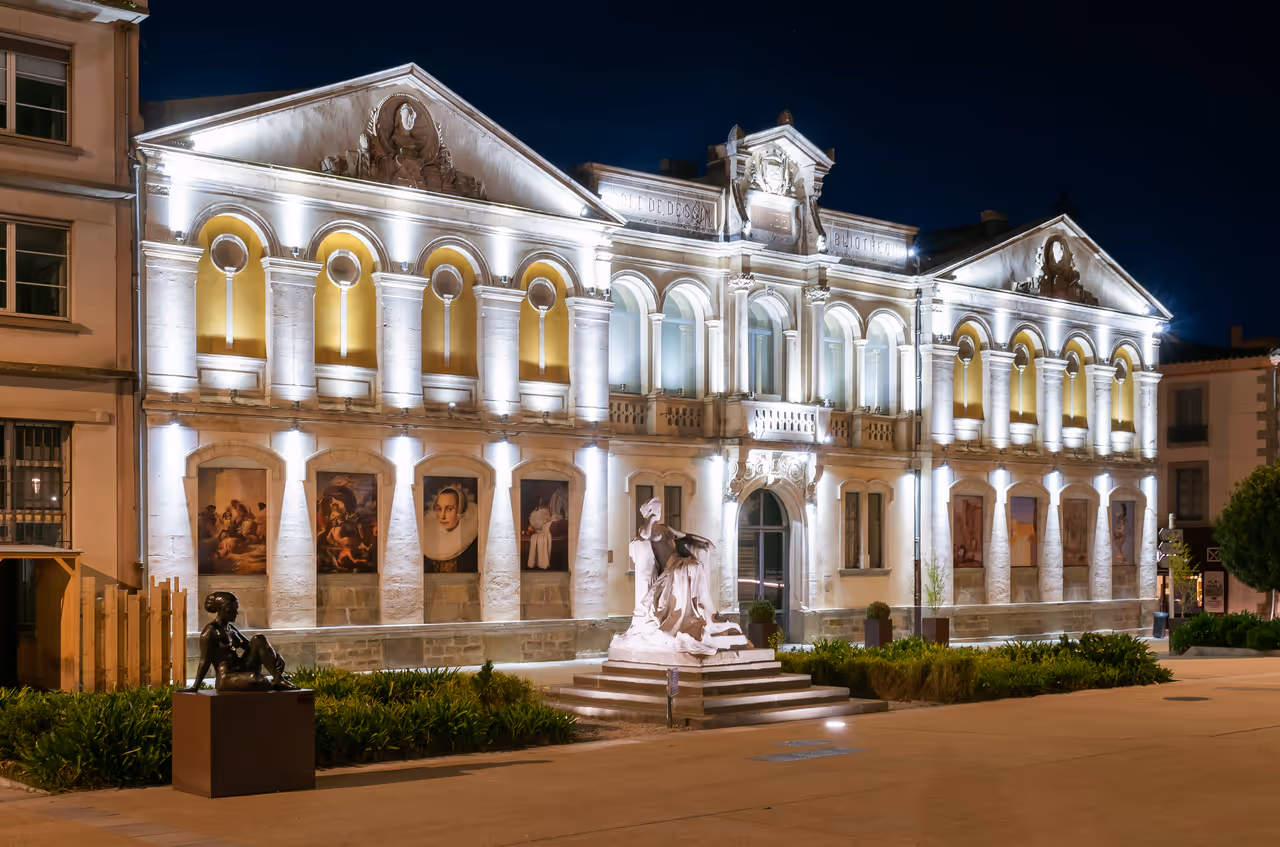 Musée des Beaux-Arts in Carcassonne beautifully illuminated at night, highlighting its classical architecture, arched windows, and outdoor sculptures