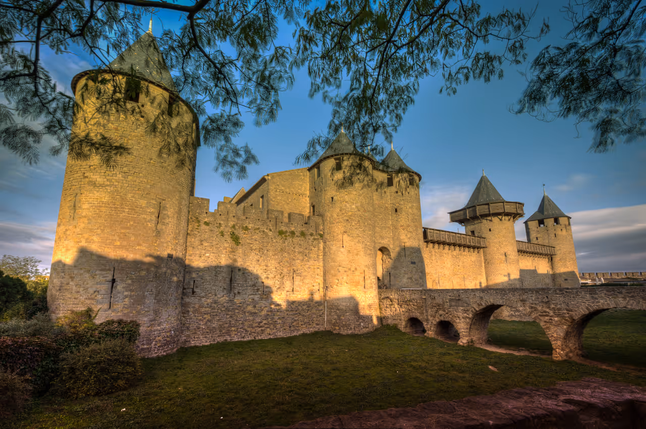 Panoramic view of the medieval stone towers and fortified walls of Château Comtal in Carcassonne under a clear blue sky