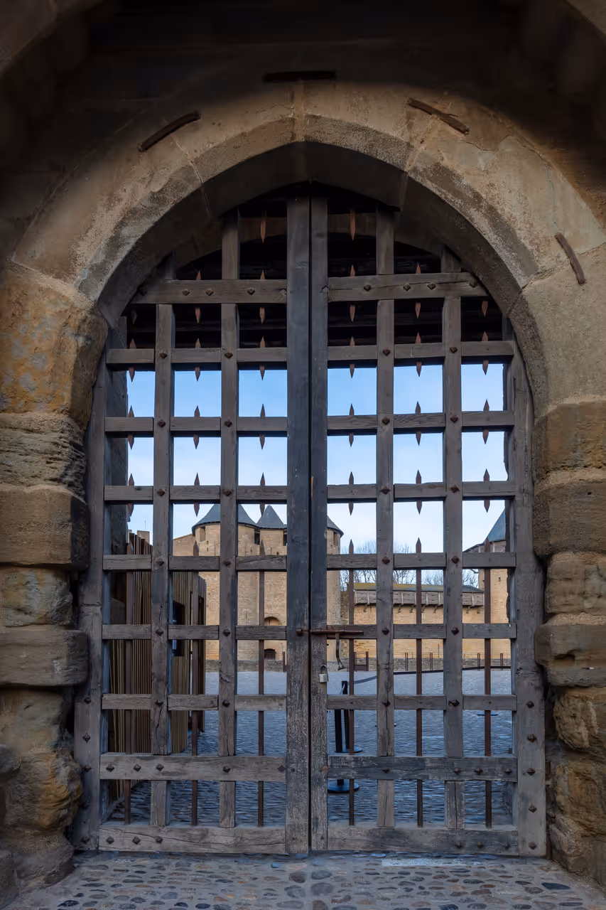 A heavy wooden and iron portcullis gate inside the medieval fortified city of Carcassonne