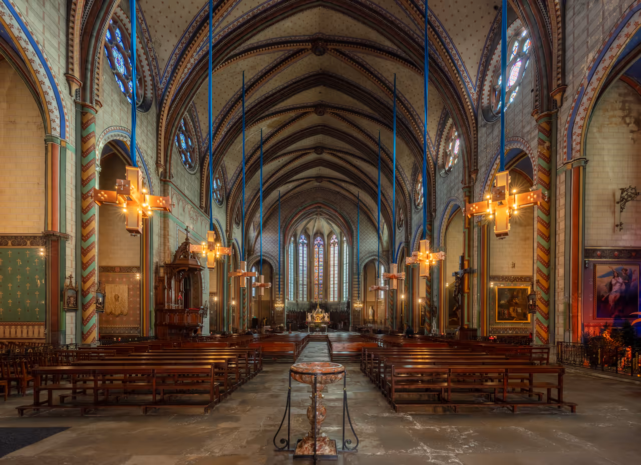 Interior view of the Gothic Cathedral of Saint Michael in Carcassonne showing the nave, ribbed vault ceilings and stained glass windows