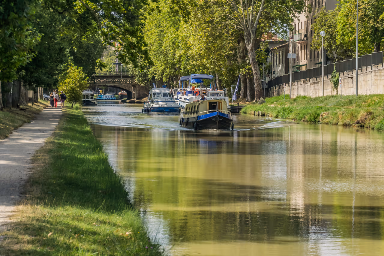 Boats cruising along the tree-lined Canal du Midi in Carcassonne