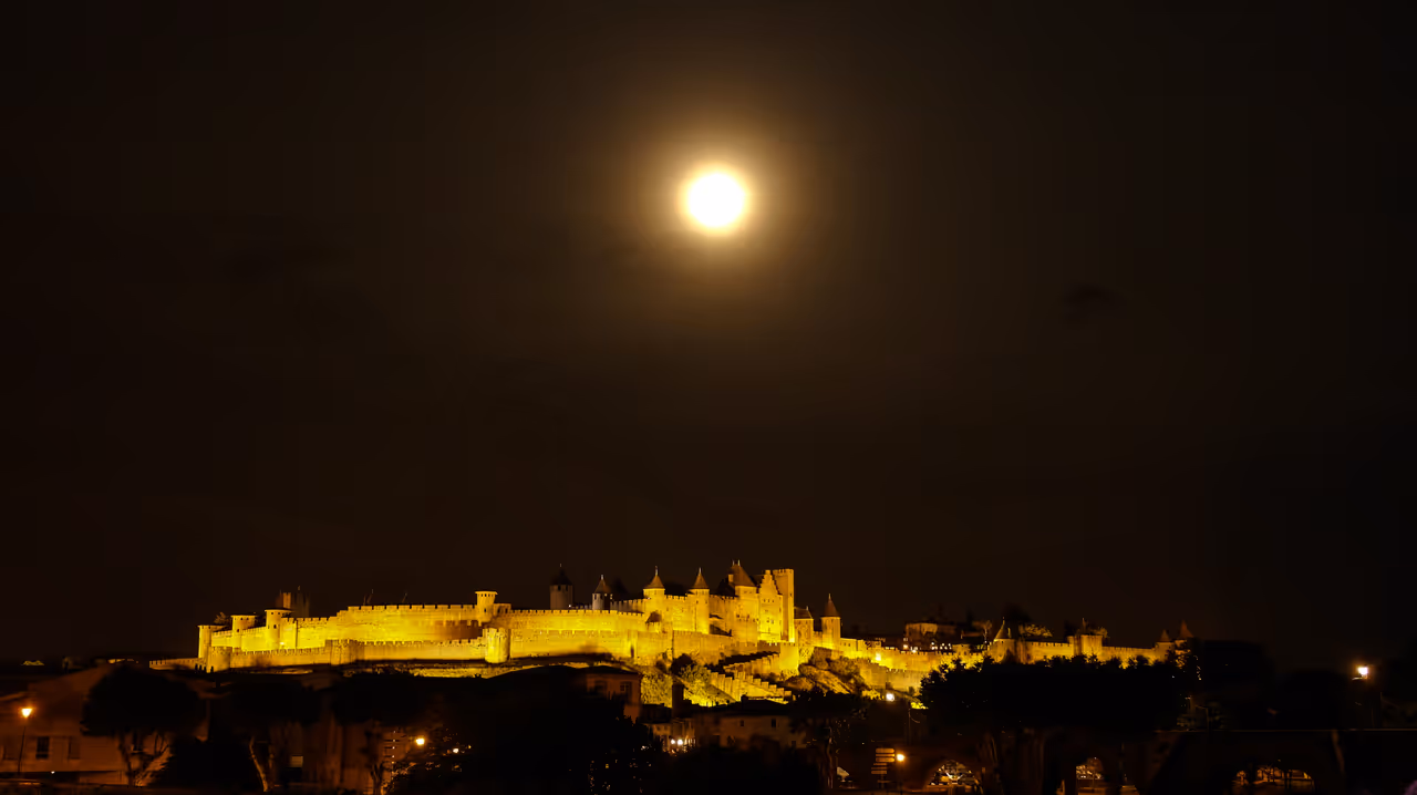 The fortified medieval citadel of the Cité de Carcassonne illuminated at night under a full moon