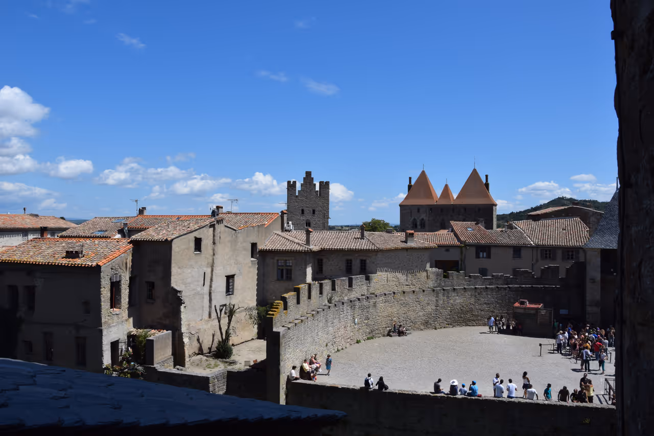 The inner courtyard and stone ramparts of the medieval fortified city of Carcassonne under a blue sky