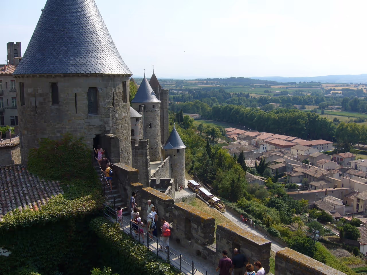 Panoramic view from the stone ramparts of the medieval fortified city of Carcassonne showing towers and turrets overlooking a town below