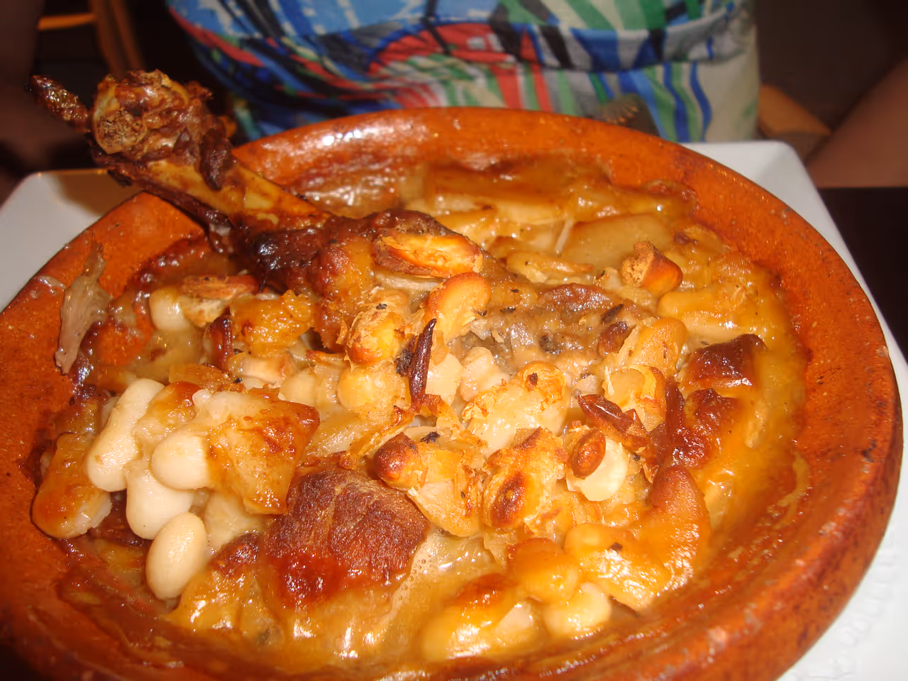 A traditional Cassoulet de Carcassonne with white beans and duck confit served in a terracotta bowl