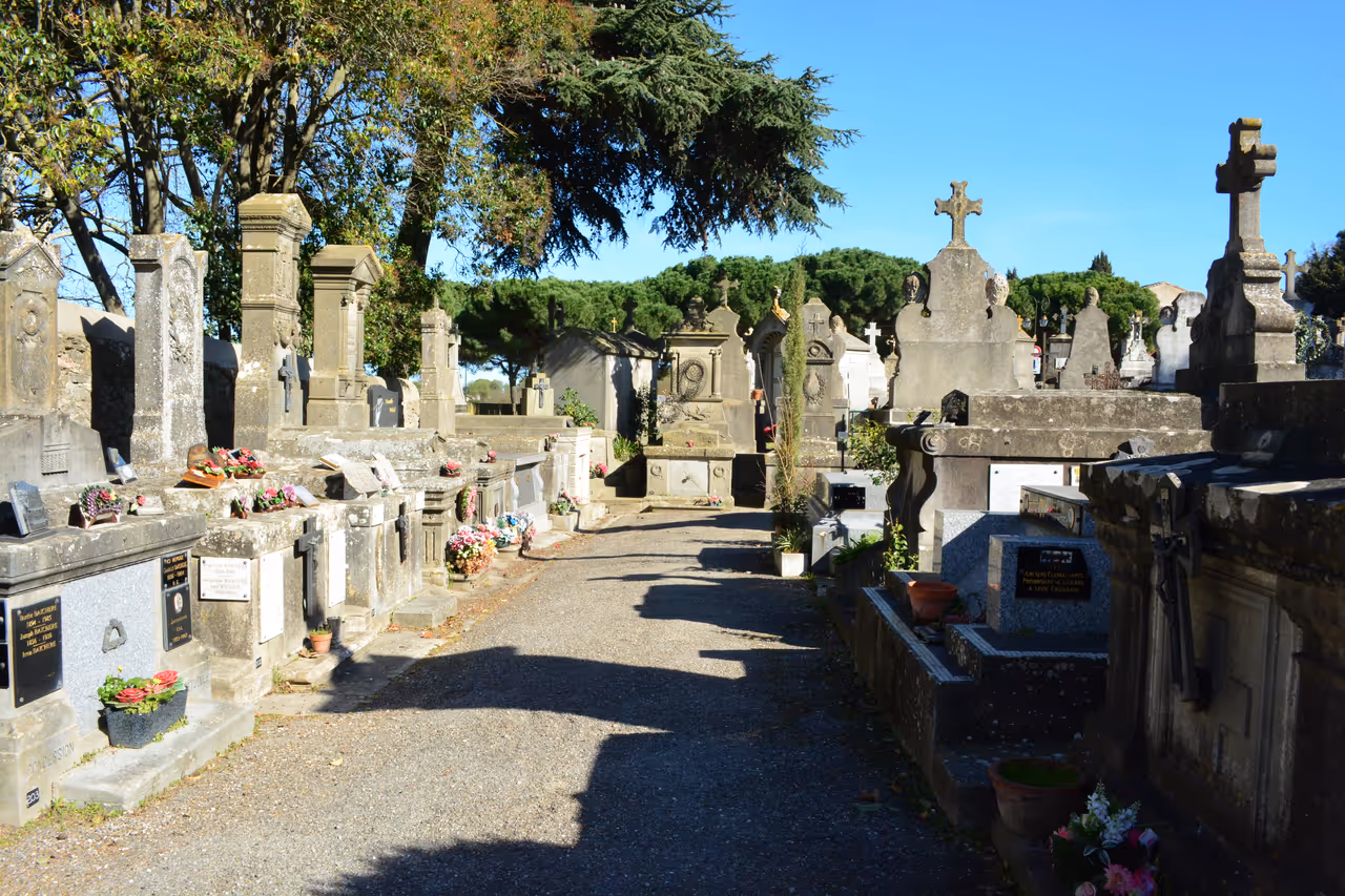 Historic Cimetière de la Cité cemetery path lined with stone graves and cross headstones in Carcassonne