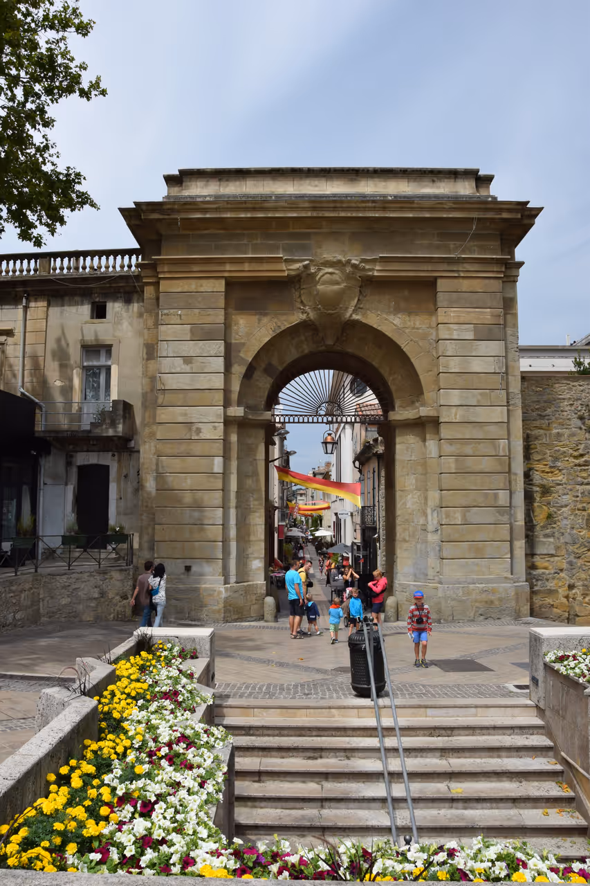 Portail des Jacobins stone archway entrance with stairs and flowers in Carcassonne