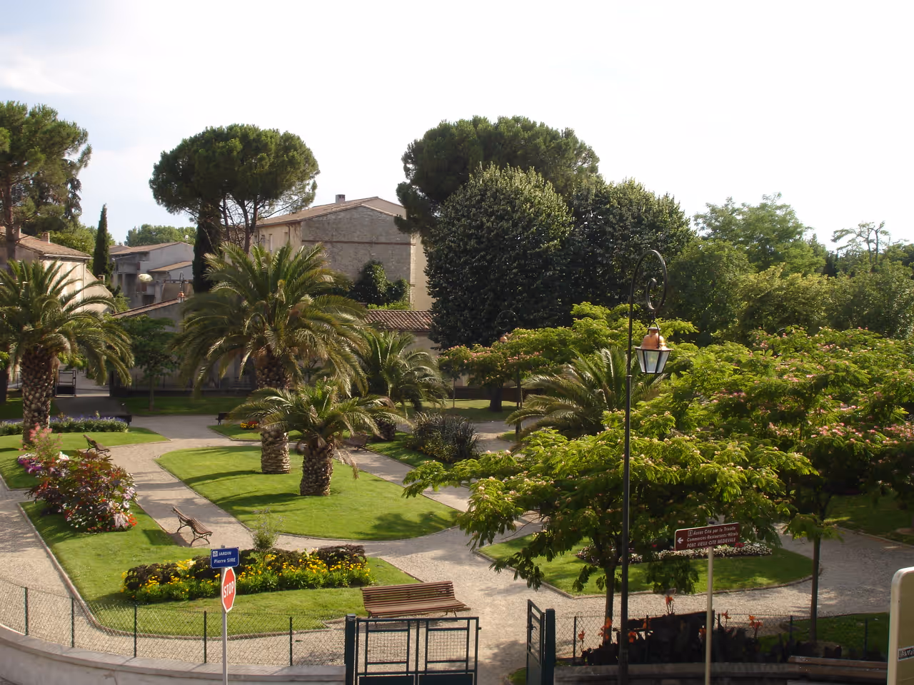 Lush green gardens of Jardin Maria et Pierre Sire in Carcassonne featuring palm trees, manicured lawns and stone walking paths