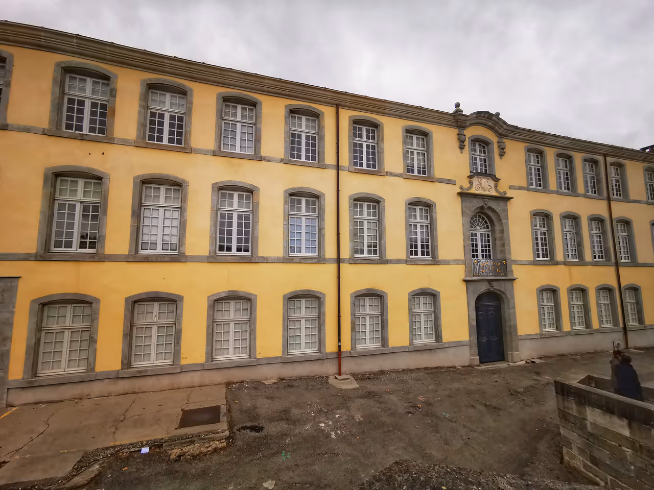 The historic Ancienne Manufacture Royale de Draps building in Carcassonne with its yellow facade and rows of arched windows