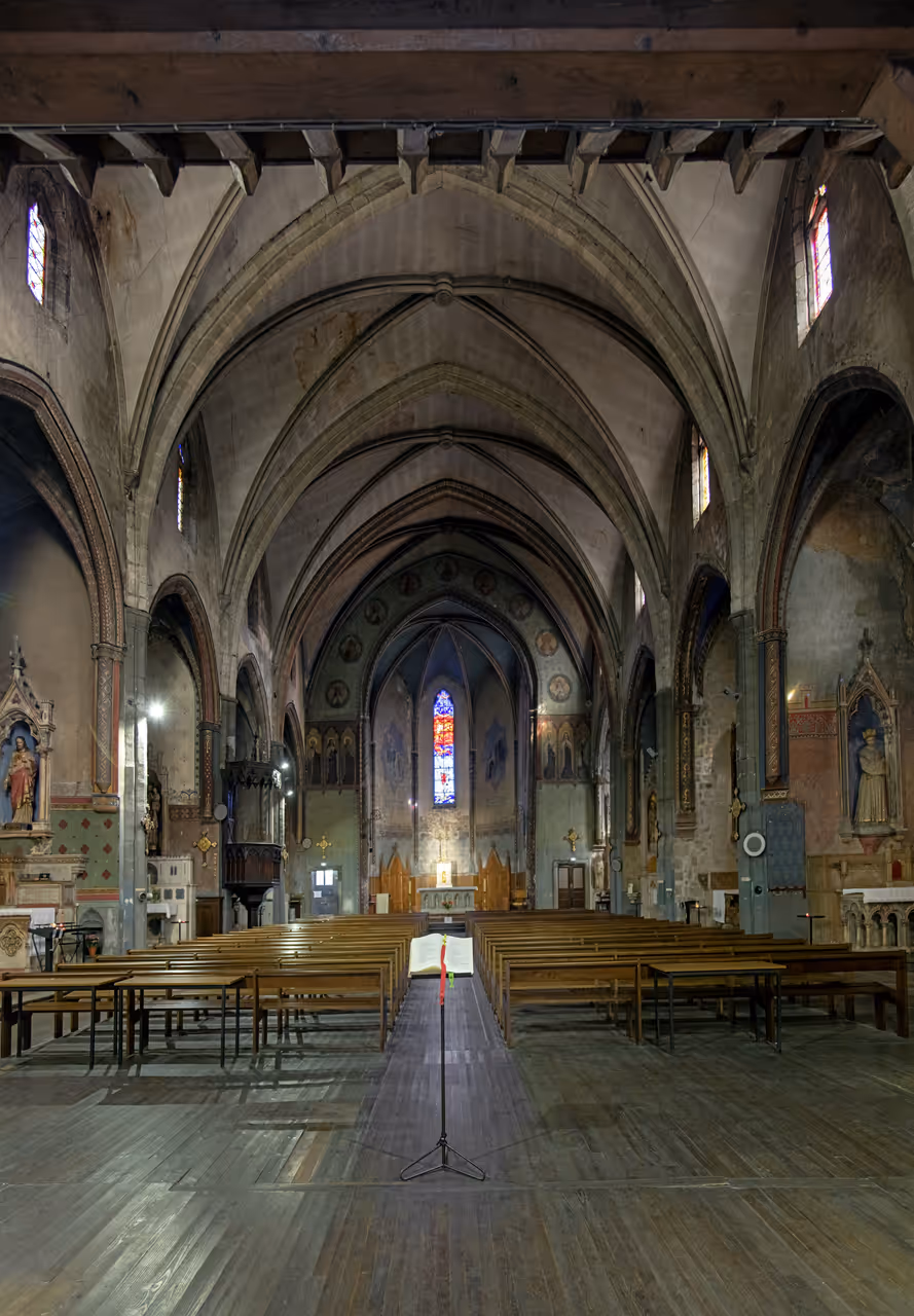 Interior of the Old Carmelite Church of Carcassonne featuring historic stone vaults and rows of wooden pews