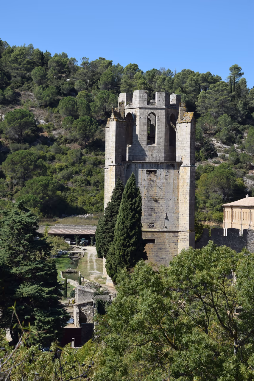Medieval bell tower of Lagrasse Abbey surrounded by green trees