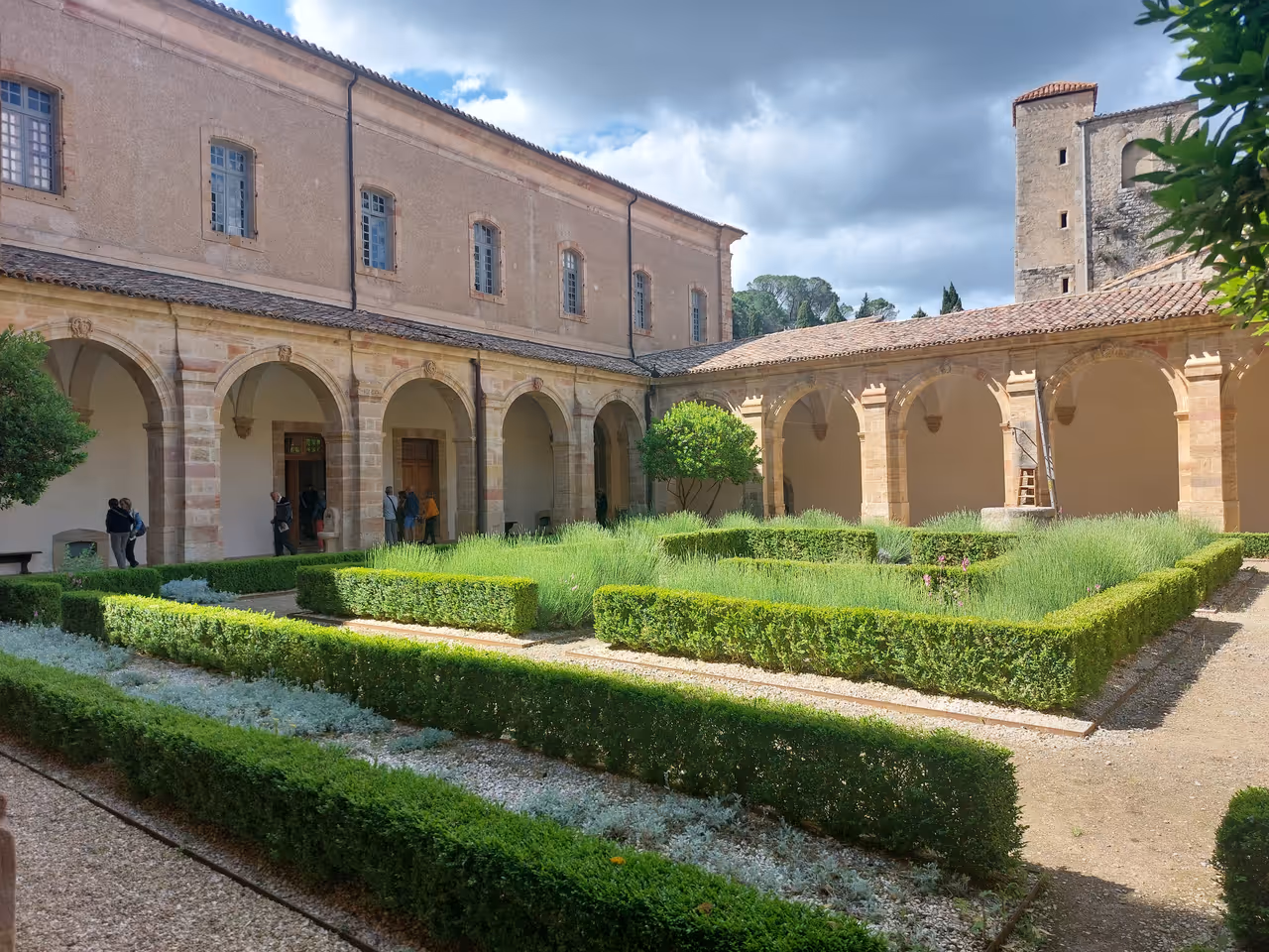 The cloister garden at Lagrasse Abbey with manicured hedges and stone arches