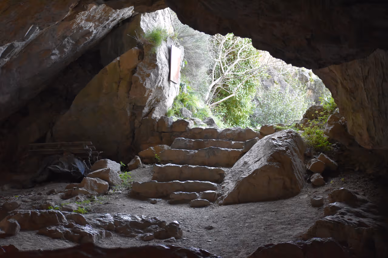 View looking out from the historic Trou de la Cité cave opening in Lastours surrounded by rocky terrain and green foliage