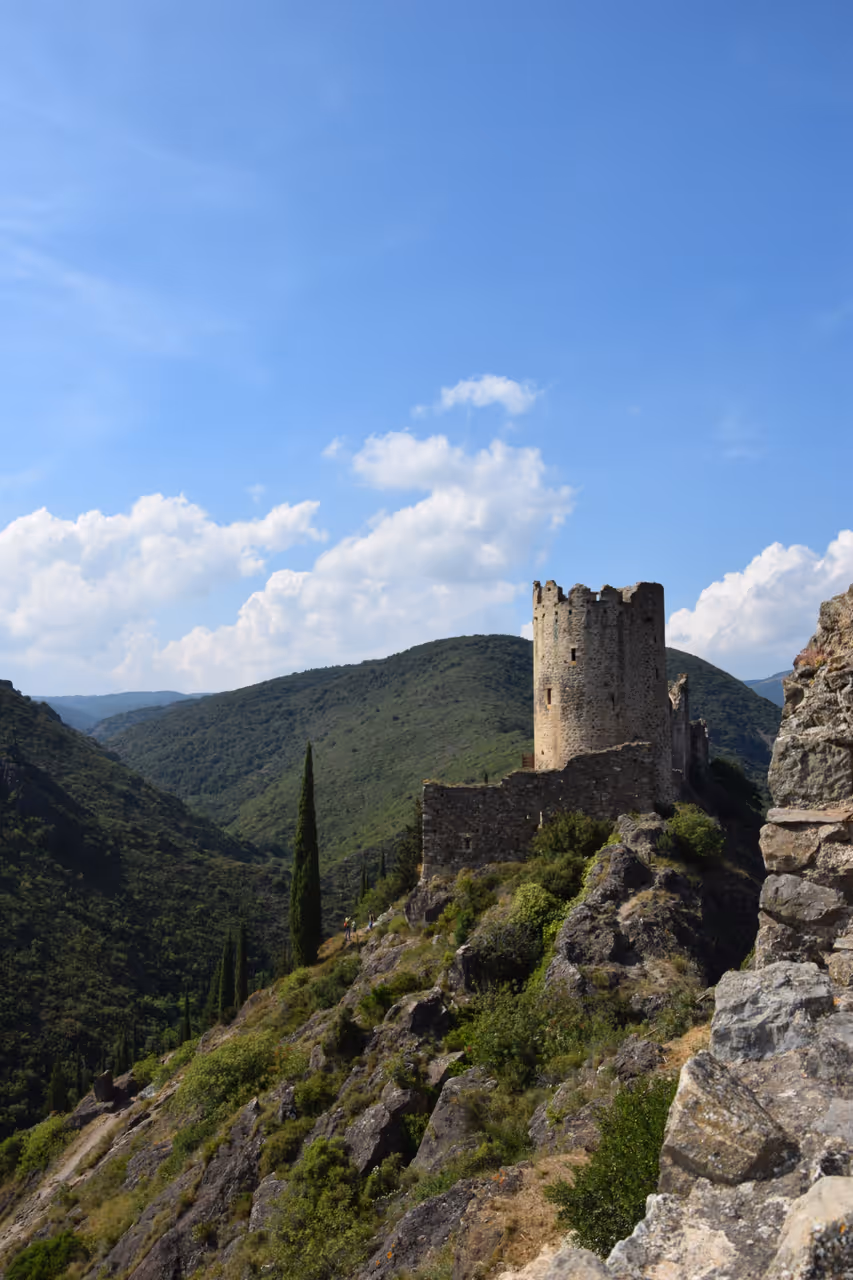 Historic stone towers of the Castles of Lastours on a rocky hilltop in a green valley