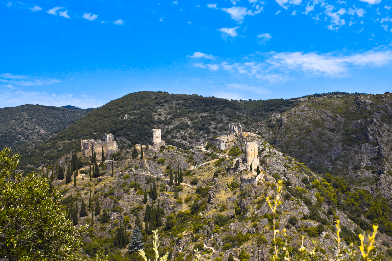 Panoramic view of the four Cathar castles of Châteaux de Lastours on a rocky ridge under a blue sky
