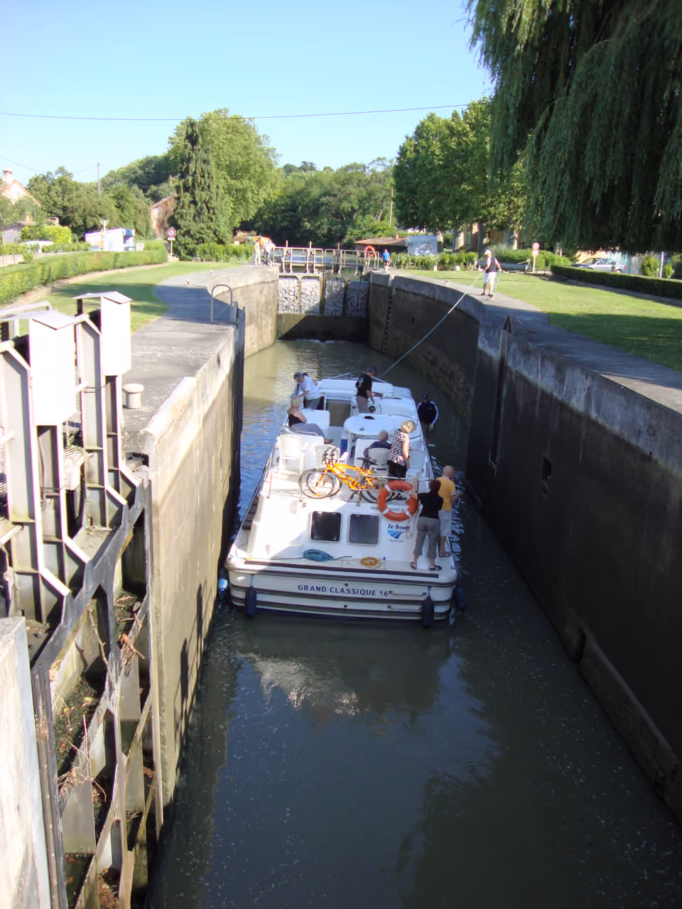 A boat navigating through the historic Montgiscard lock on the Canal du Midi surrounded by lush greenery