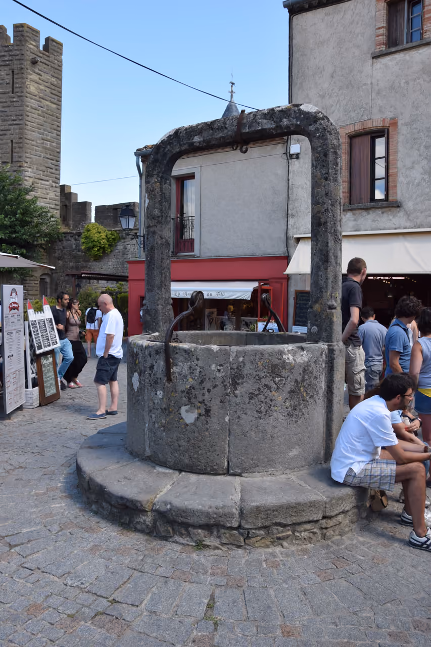 Ancient stone water well in a medieval town square with tourists