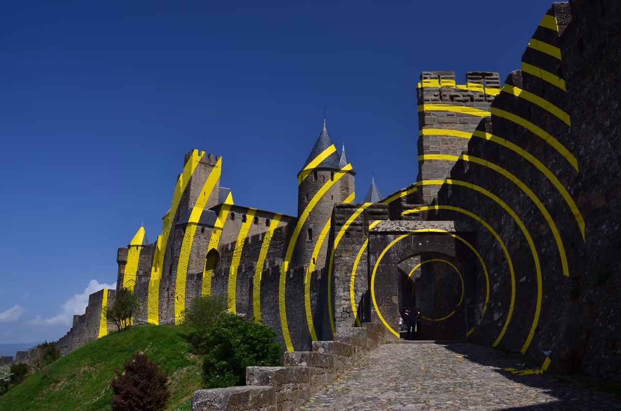 Yellow concentric circles of Felice Varini anamorphic art installation on the stone walls and towers of the medieval Cité de Carcassonne fortress