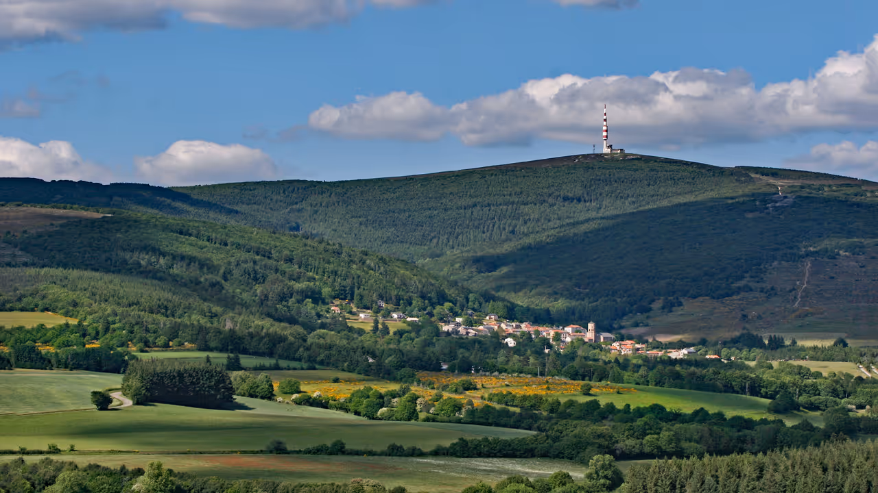 Panoramic view of Pradelles-Cabardes village nestled below the forested slopes and communication tower of Pic de Nore