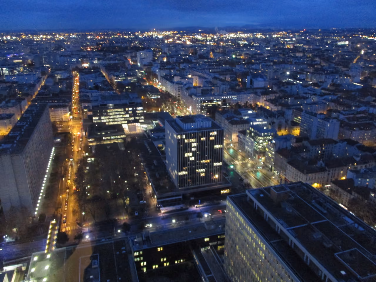Night view of a cityscape and illuminated streets from a high-rise rooftop restaurant bar