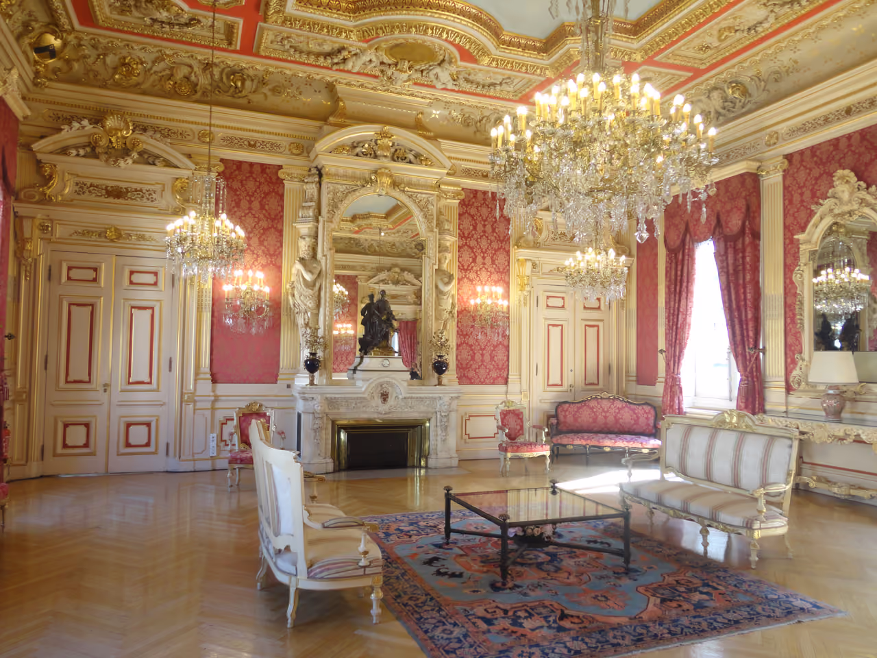 Ornate red salon room with gilded decor and chandeliers inside Lyon City Hall