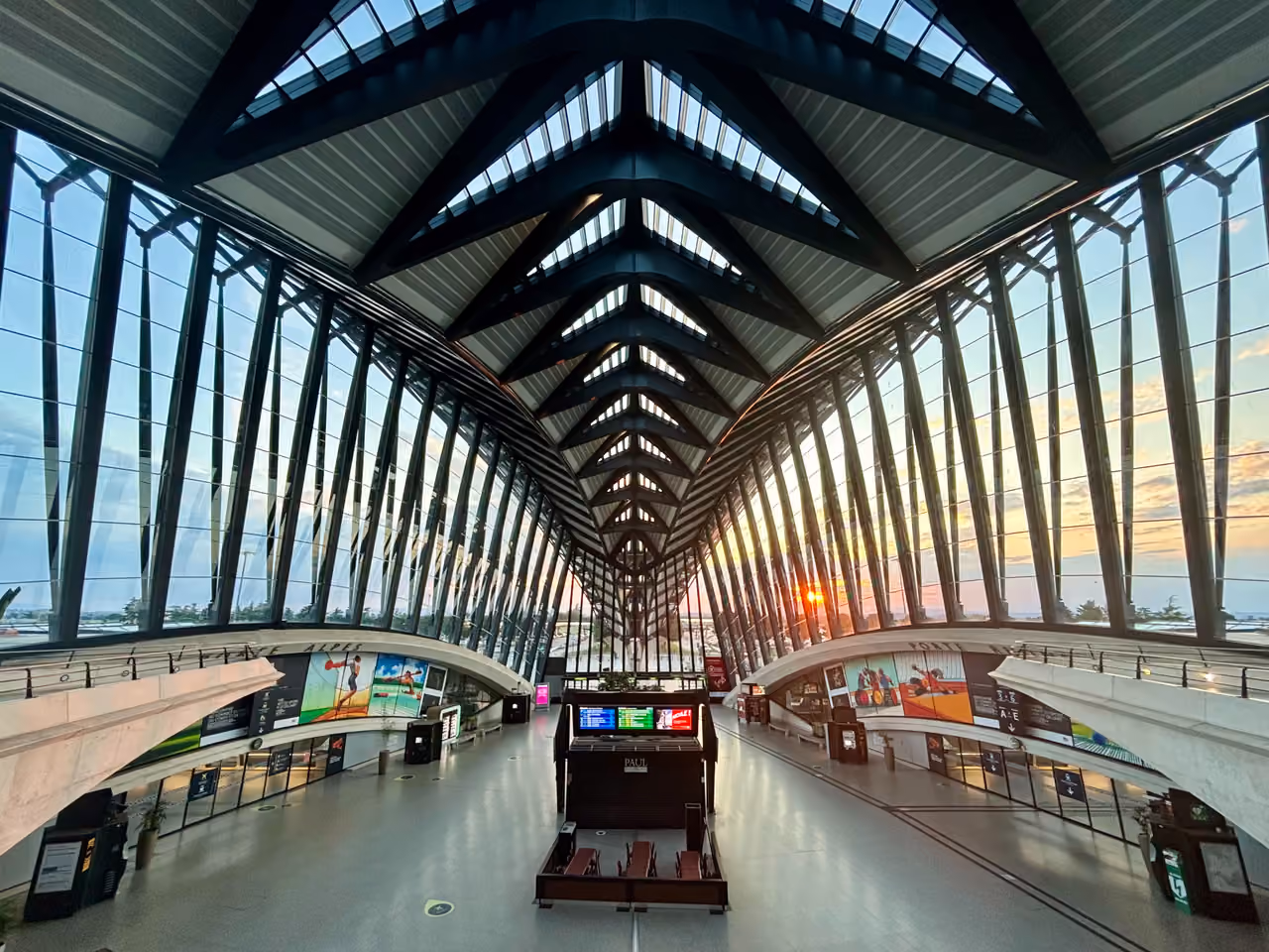 Modern architecture of the Lyon-Saint Exupery railway station interior with dramatic ribbed ceiling and large glass windows at sunset