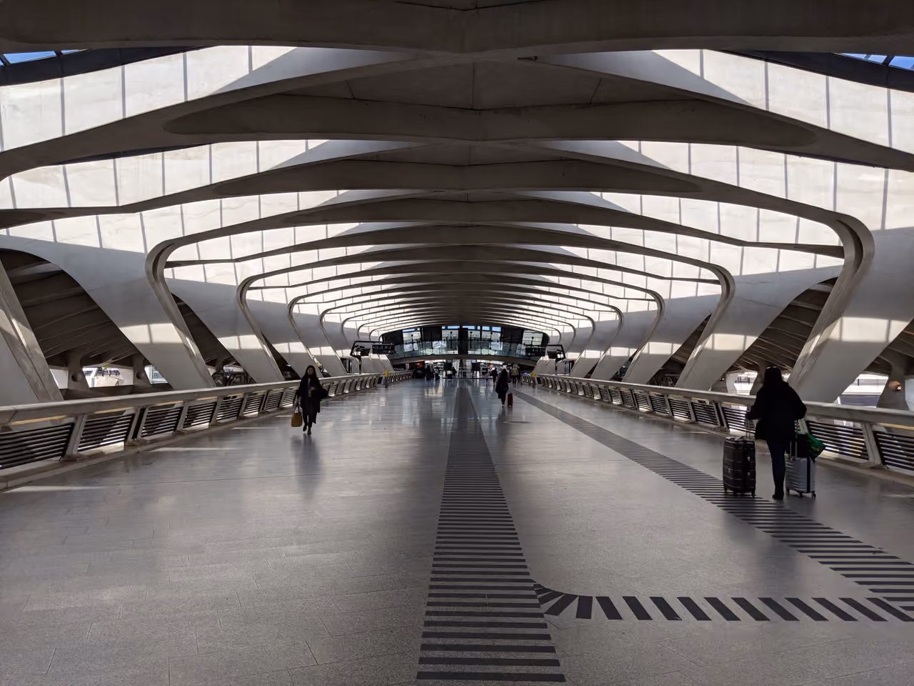 Interior of the modern Lyon-Saint-Exupéry TGV railway station with futuristic curved architecture and travellers walking down the main concourse