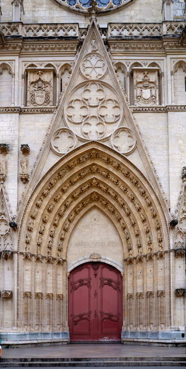 Gothic portal of Saint Jean Cathedral with arched stonework and red doors