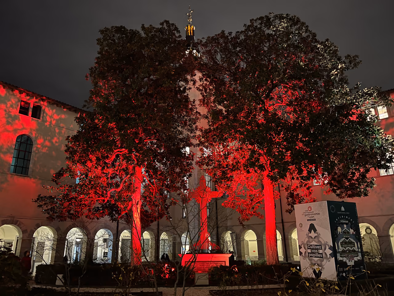 Courtyard of the historic Grand Hotel Dieu illuminated with vibrant red lights at night