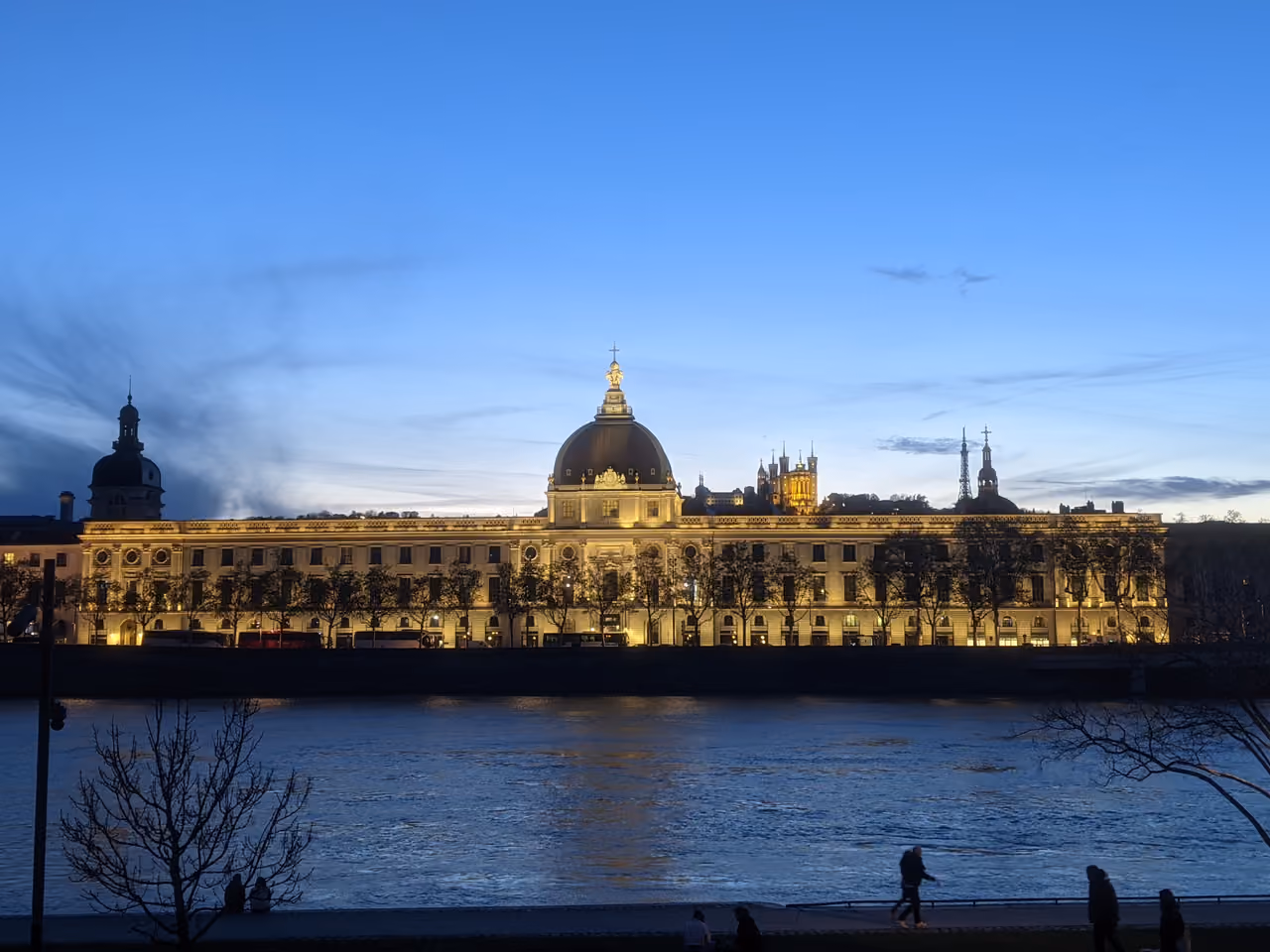 The Grand Hotel-Dieu illuminated at twilight along the Rhone River bank