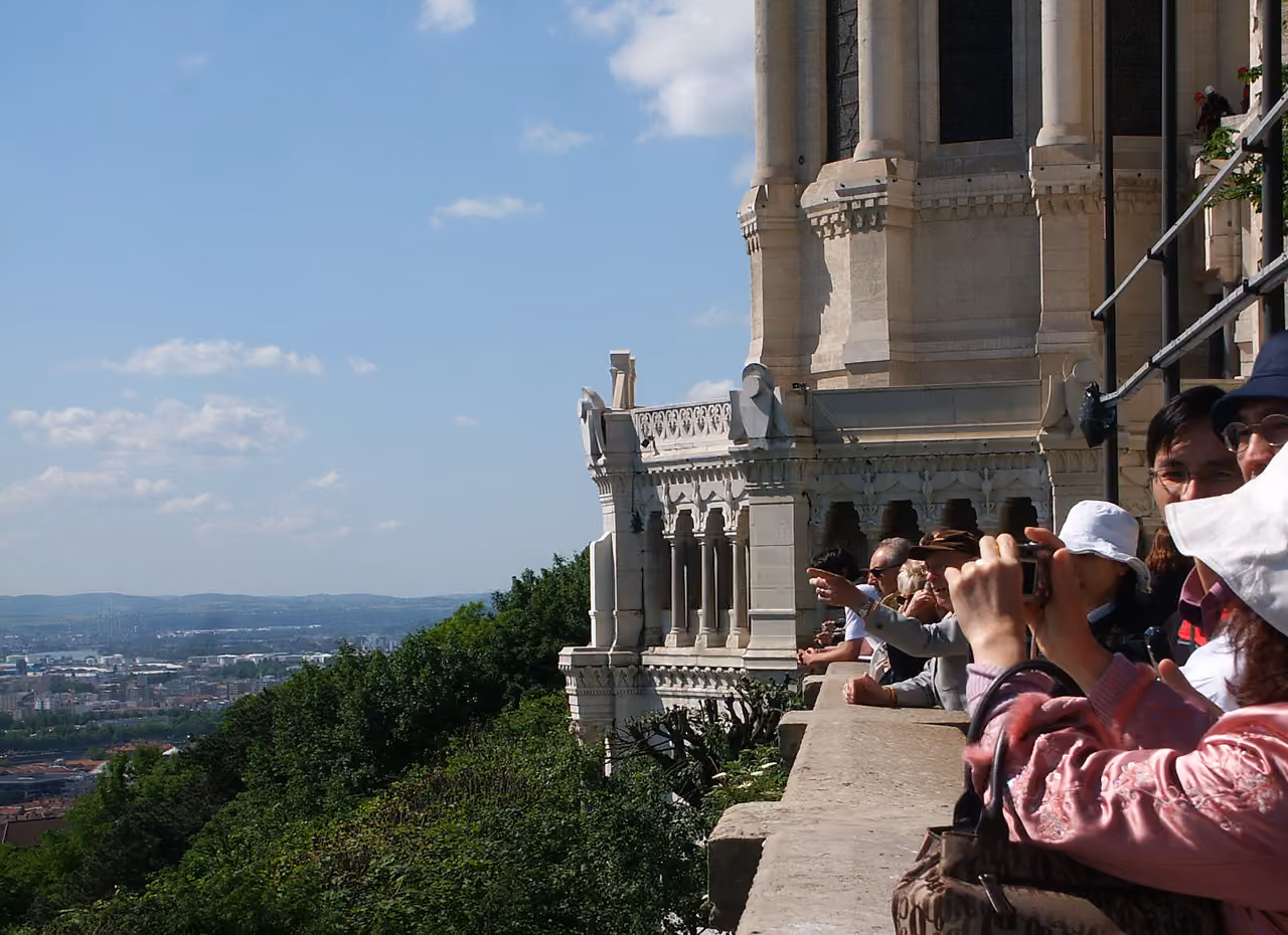 Tourists admiring the panoramic city view from the terrace of the Basilica of Notre-Dame de Fourviere