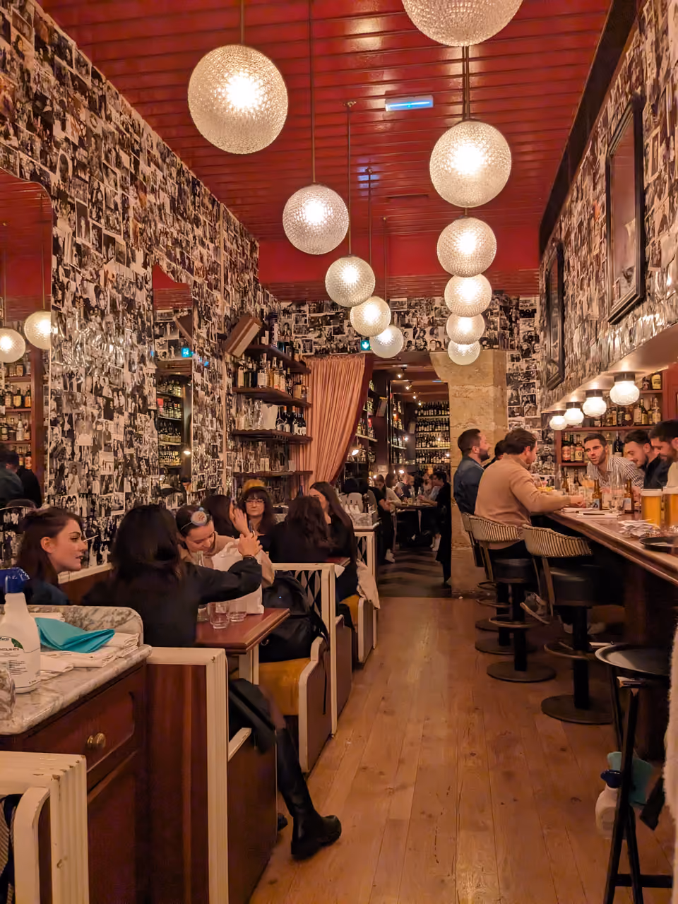 Vibrant interior of Carmelo restaurant in Lyon featuring a busy dining room with spherical pendant lights and walls covered in framed photos