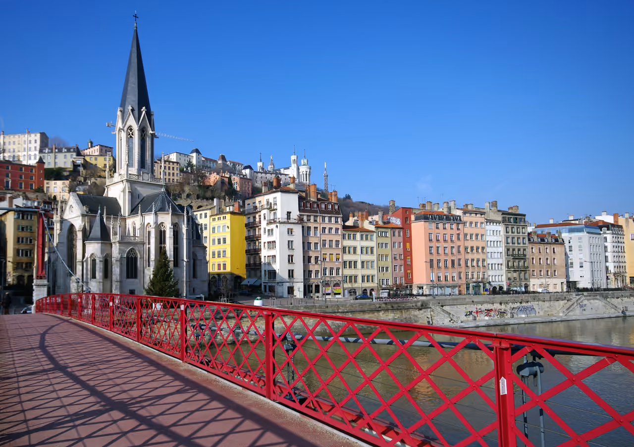 View of Église Saint-Georges and colorful buildings along the Saône river from the red footbridge