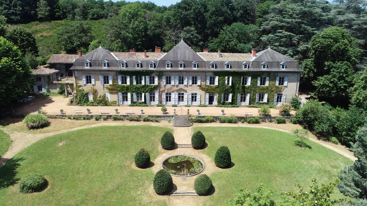 Aerial drone view of a historic country estate with symmetrical manicured gardens and a central pond