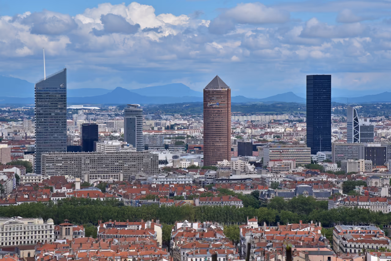 Skyline view of skyscrapers in the Part-Dieu district of Lyon featuring Tour Incity and Tour Part-Dieu rising above red-roofed city buildings