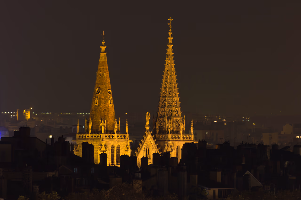 Night view of the illuminated asymmetrical spires of Saint-Nizier church