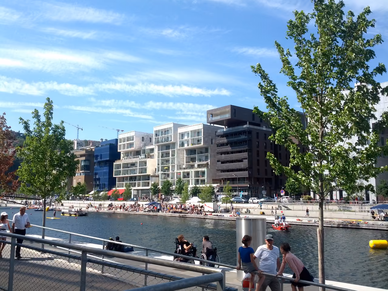 Sunny waterfront promenade and modern apartment buildings in the Confluence district