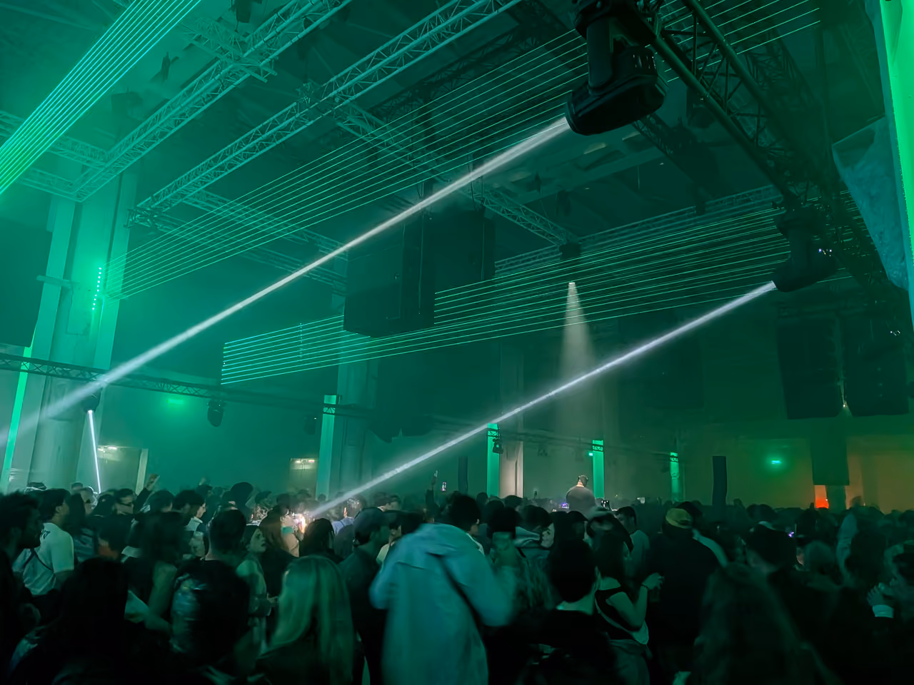 Electronic music concert crowd under green laser lights at La Sucriere during Nuits Sonores festival in Lyon