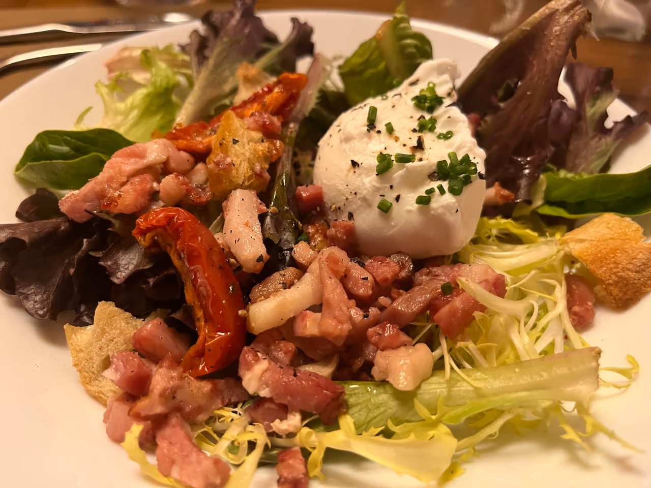 Traditional Lyonnaise salad with a poached egg, bacon lardons and crisp croutons