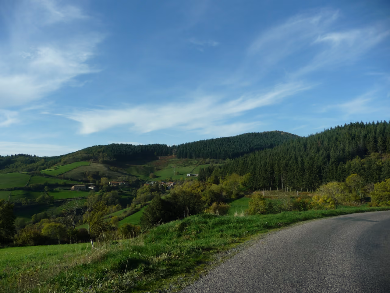 Scenic paved road overlooking rolling green hills and a forested valley near Mont Soubran