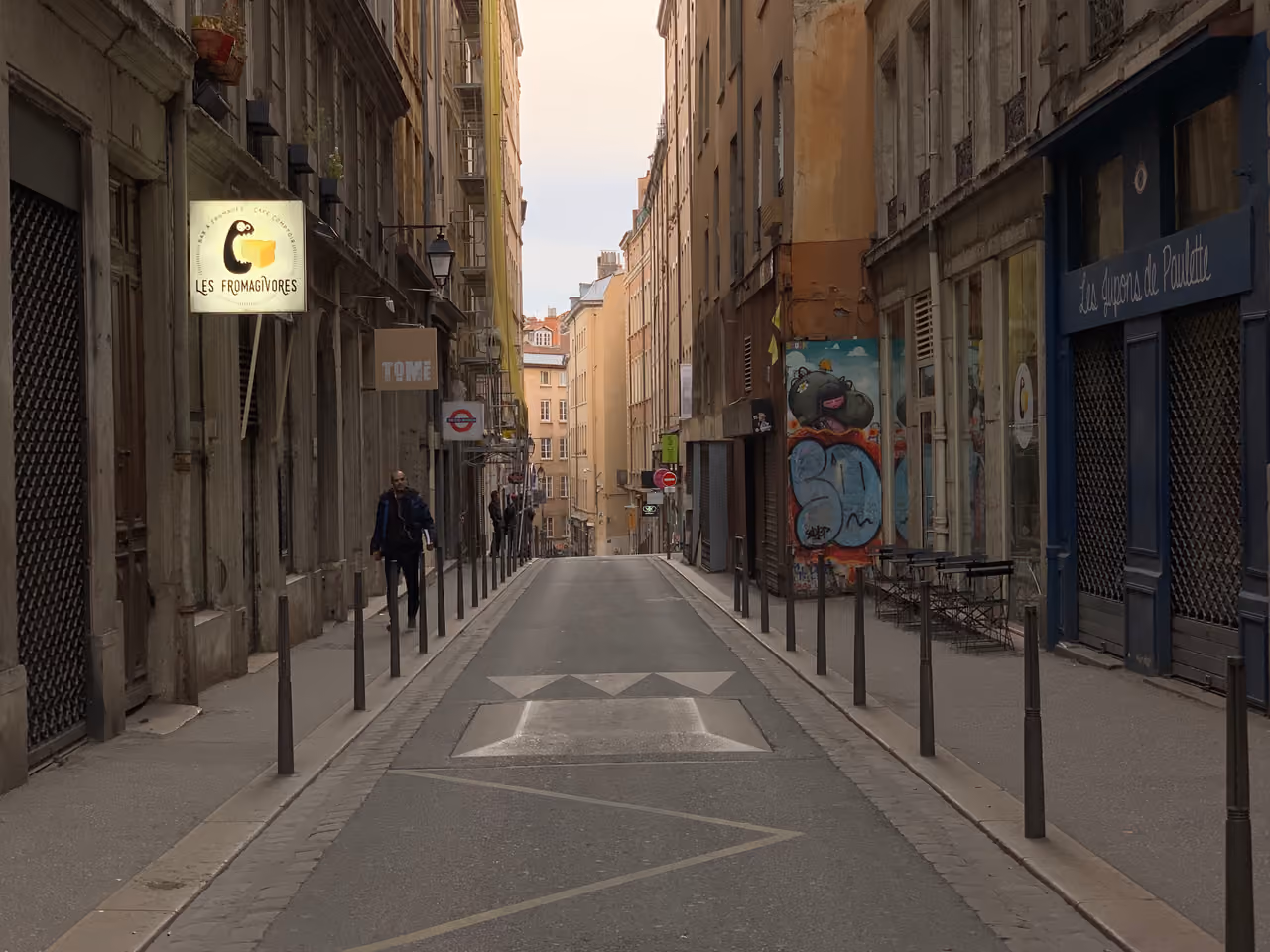 Narrow street with historic buildings, a small cheese restaurant sign, and cobblestone pathways