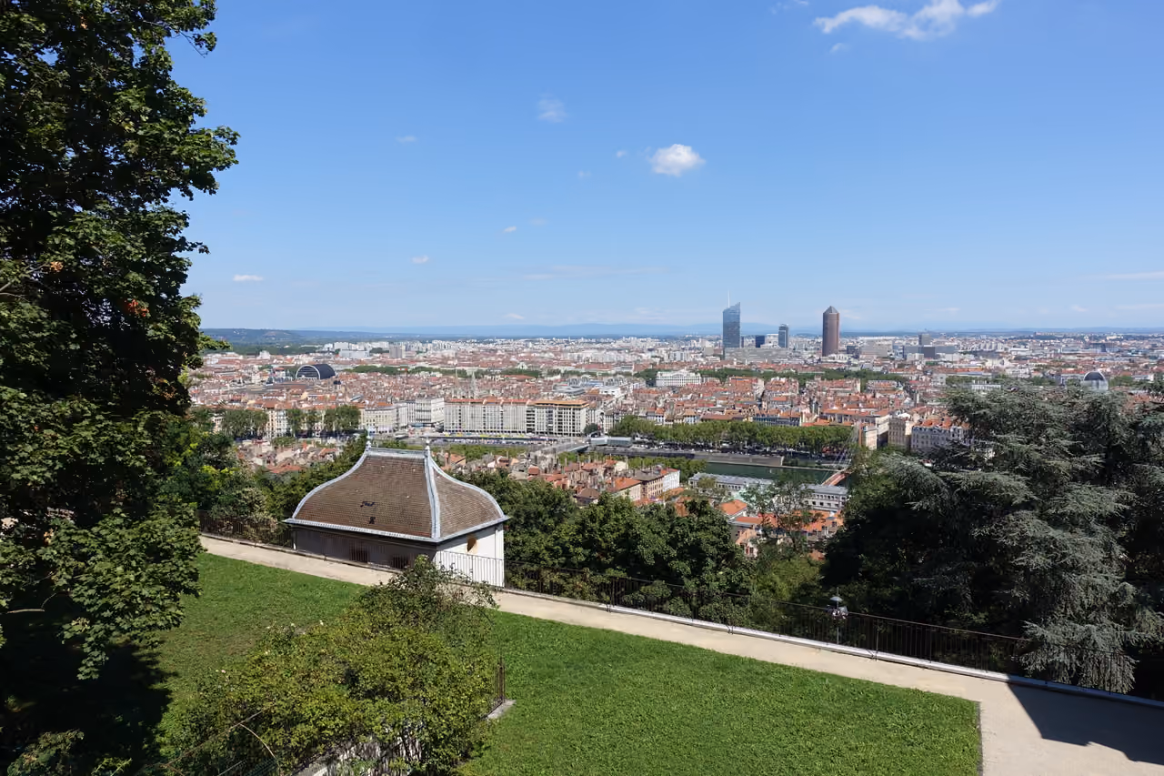 Panoramic view of a city skyline with skyscrapers and historic buildings from an elevated park viewpoint