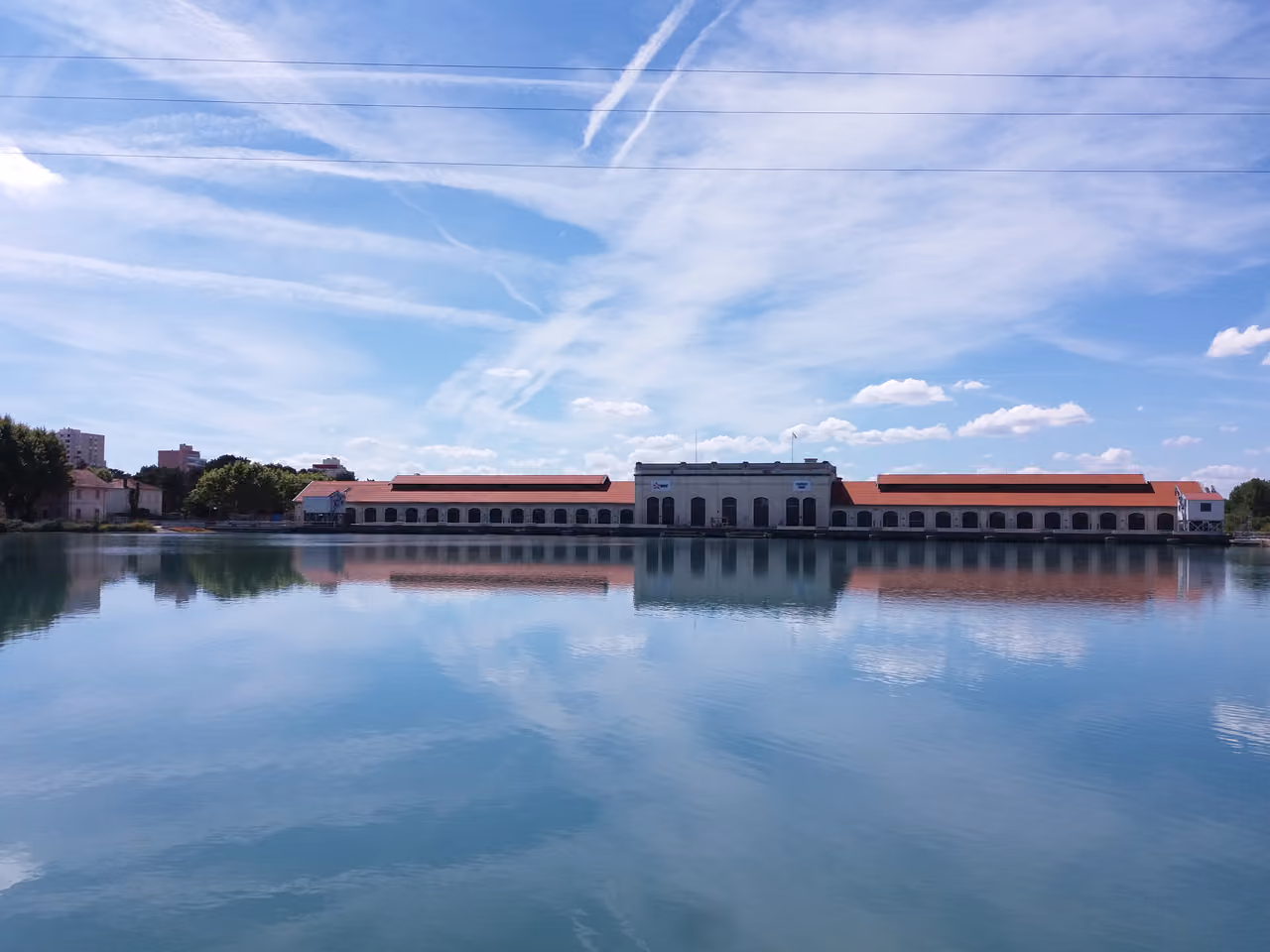 Hydroelectric station on the Canal de Jonage in France viewed from the water with reflections under a blue sky