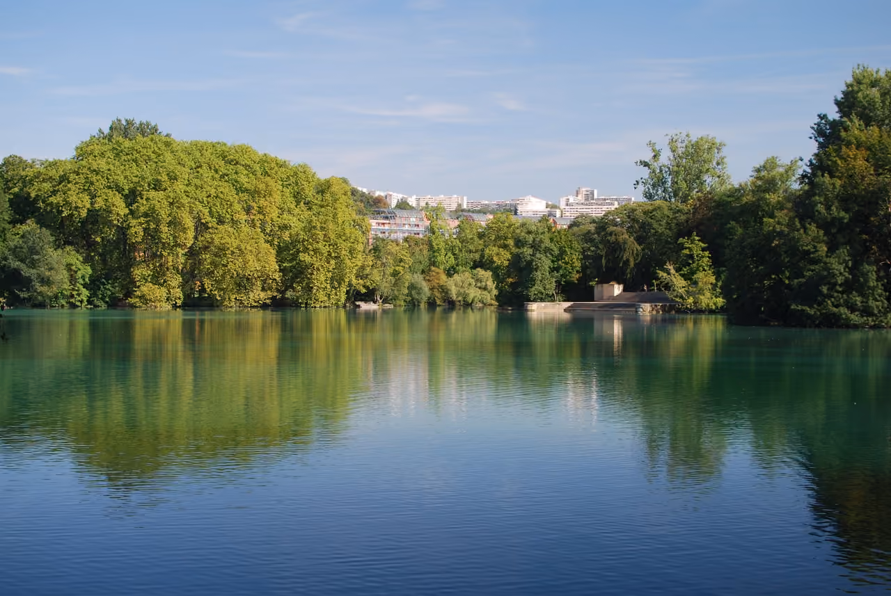Scenically wooded banks of the lake at Parc de la Tête d'Or with calm water reflections