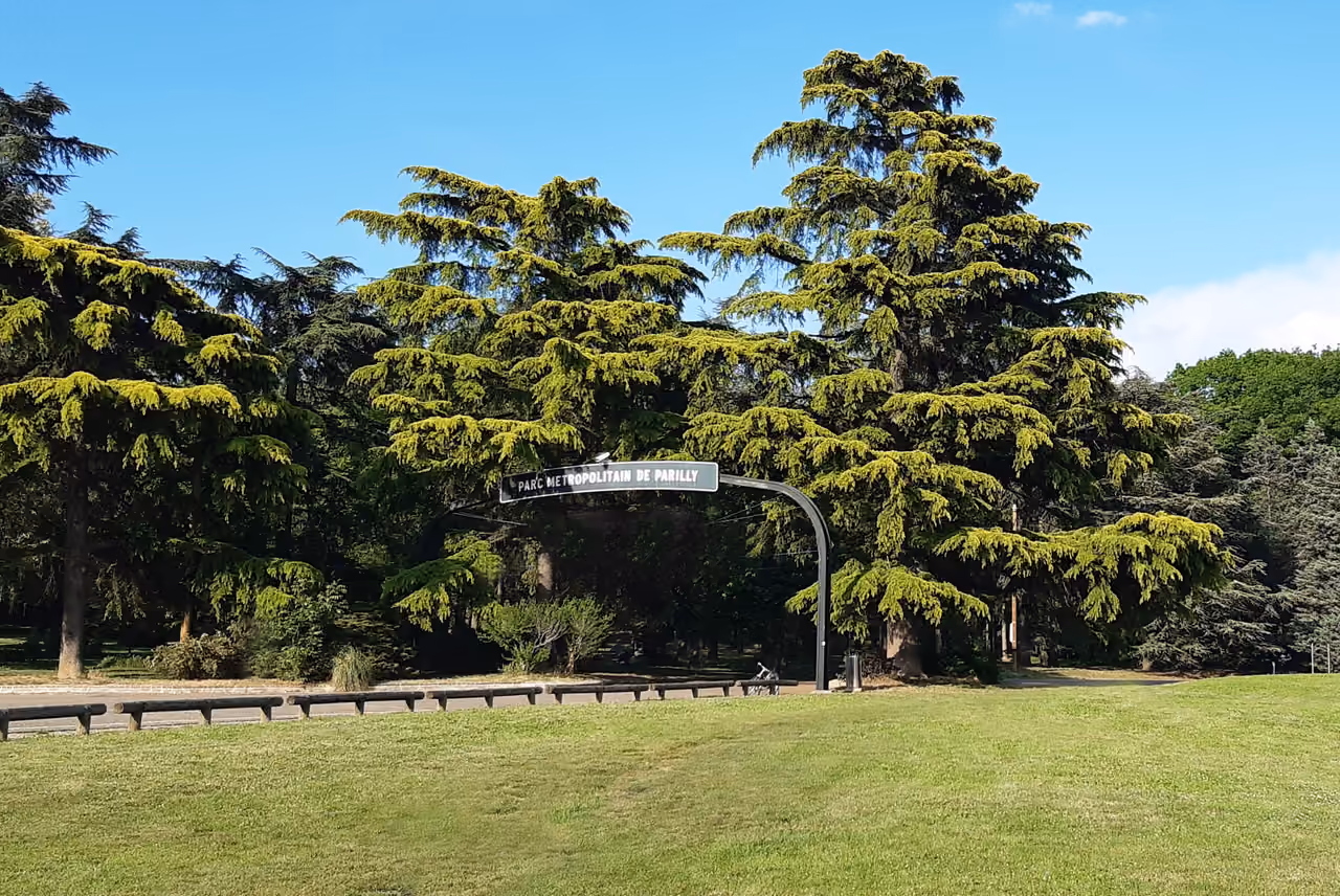 The entrance archway of Parc Métropolitain de Parilly surrounded by large cedar trees and green lawns