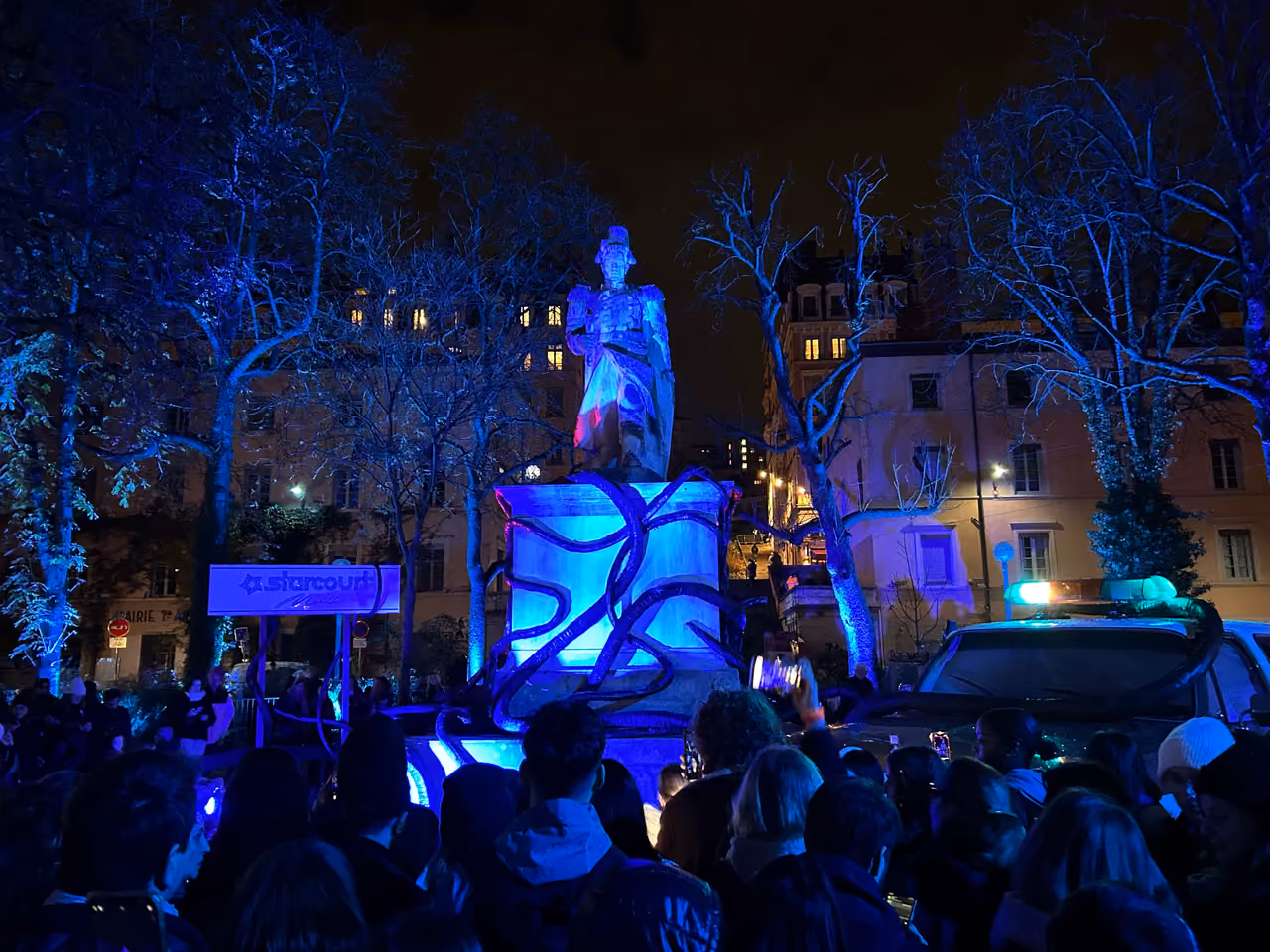 Crowd watching the Stranger Things themed light display on a statue during the Festival of Lights