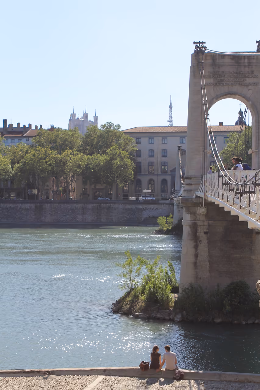 Passer-by crossing the Passerelle Saint-Georges suspension bridge over the Saone river with a view towards the historic city center of Lyon