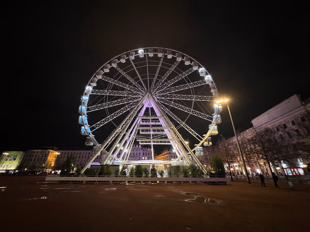 Large Ferris wheel illuminated at night in Place Bellecour square