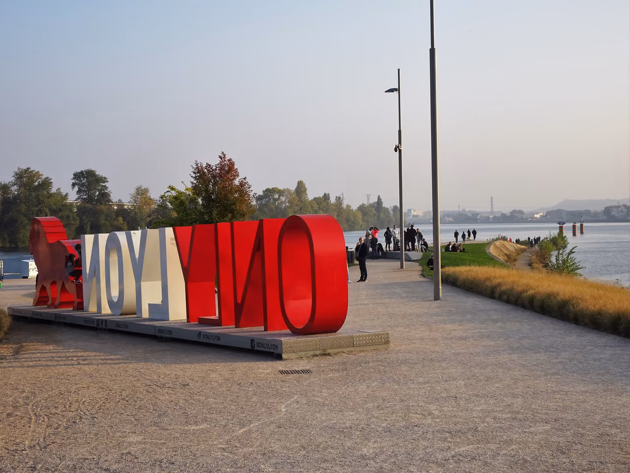 Large red and white ONLYLYON sign and lion sculpture at the confluence of the Rhone and Saone rivers